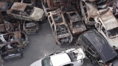 Bu video Irpin, Bucha bölgesinde, gri, düz, renksiz, yanmış arabaları gösteriyor.