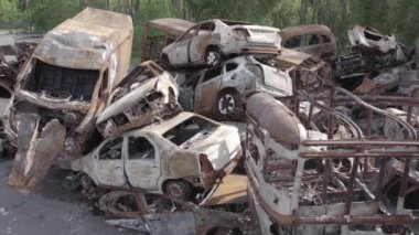 Bu video Irpin, Bucha bölgesinde, gri, düz, renksiz, yanmış arabaları gösteriyor.