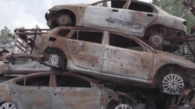 Bu video Irpin, Bucha bölgesinde, gri, düz, renksiz, yanmış arabaları gösteriyor.