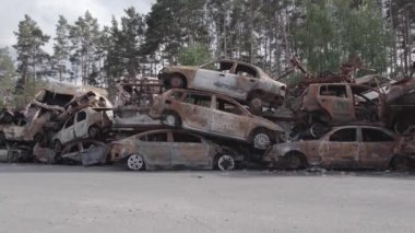 Bu video Irpin, Bucha bölgesinde, gri, düz, renksiz, yanmış arabaları gösteriyor.