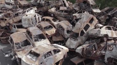 Bu video Irpin, Bucha bölgesinde, gri, düz, renksiz, yanmış arabaları gösteriyor.
