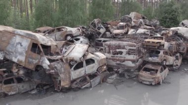Bu video Irpin, Bucha bölgesinde, gri, düz, renksiz, yanmış arabaları gösteriyor.