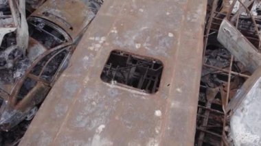 Bu video Irpin, Bucha bölgesinde, gri, düz, renksiz, yanmış arabaları gösteriyor.