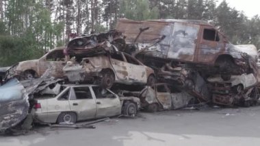 Bu video Irpin, Bucha bölgesinde, gri, düz, renksiz, yanmış arabaları gösteriyor.