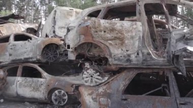 Bu video Irpin, Bucha bölgesinde, gri, düz, renksiz, yanmış arabaları gösteriyor.