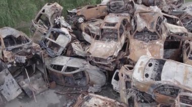 Bu video Irpin, Bucha bölgesinde, gri, düz, renksiz, yanmış arabaları gösteriyor.