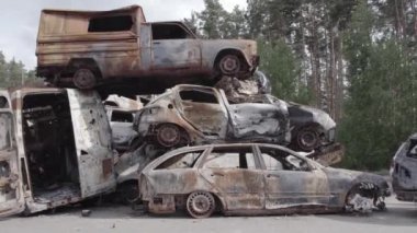 Bu video Irpin, Bucha bölgesinde, gri, düz, renksiz, yanmış arabaları gösteriyor.