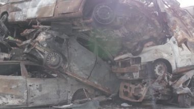 Bu video Irpin, Bucha bölgesinde, gri, düz, renksiz, yanmış arabaları gösteriyor.