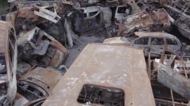 Bu video Irpin, Bucha bölgesinde, gri, düz, renksiz, yanmış arabaları gösteriyor.