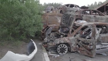 Bu video Irpin, Bucha bölgesinde, gri, düz, renksiz, yanmış arabaları gösteriyor.