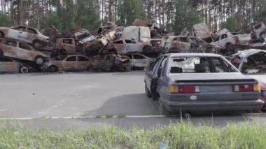 Bu video Irpin, Bucha bölgesinde, gri, düz, renksiz, yanmış arabaları gösteriyor.
