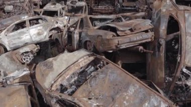 Bu video Irpin, Bucha bölgesinde, gri, düz, renksiz, yanmış arabaları gösteriyor.