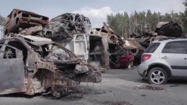 Bu video Irpin, Bucha bölgesinde, gri, düz, renksiz, yanmış arabaları gösteriyor.