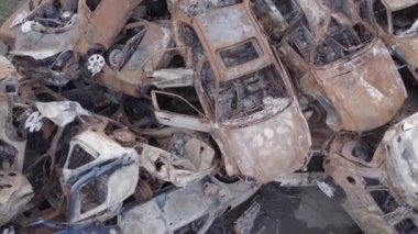 Bu video Irpin, Bucha bölgesinde, gri, düz, renksiz, yanmış arabaları gösteriyor.