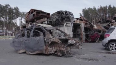 Bu video Irpin, Bucha bölgesinde, gri, düz, renksiz, yanmış arabaları gösteriyor.