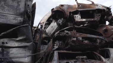 Bu video Irpin, Bucha bölgesinde, gri, düz, renksiz, yanmış arabaları gösteriyor.