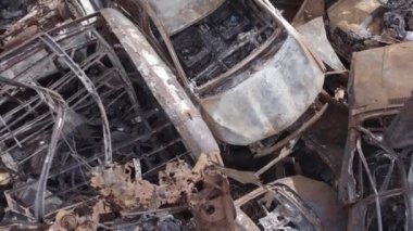 Bu video Irpin, Bucha bölgesinde, gri, düz, renksiz, yanmış arabaları gösteriyor.