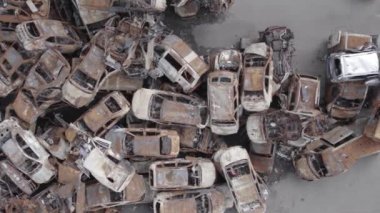 Bu video Irpin, Bucha bölgesinde, gri, düz, renksiz, yanmış arabaları gösteriyor.