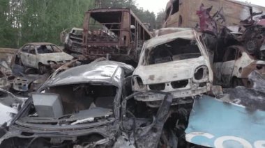 Bu video Irpin, Bucha bölgesinde, gri, düz, renksiz, yanmış arabaları gösteriyor.