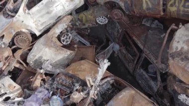 Bu video Irpin, Bucha bölgesinde, gri, düz, renksiz, yanmış arabaları gösteriyor.