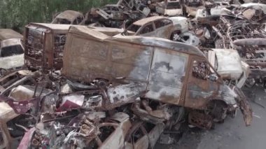 Bu video Irpin, Bucha bölgesinde, gri, düz, renksiz, yanmış arabaları gösteriyor.