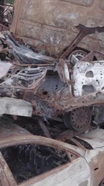 Bu stok dikey video Irpin, Bucha bölgesinde gri, düz, renksiz, yanmış arabaları gösteriyor.