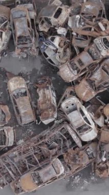 Bu stok dikey video Irpin, Bucha bölgesinde gri, düz, renksiz, yanmış arabaları gösteriyor.