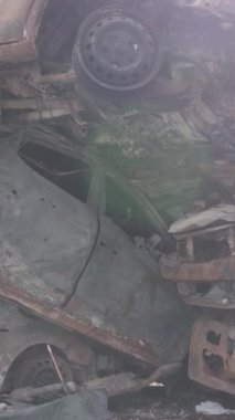 Bu stok dikey video Irpin, Bucha bölgesinde gri, düz, renksiz, yanmış arabaları gösteriyor.