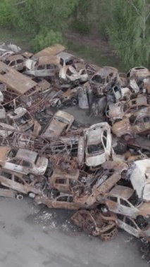 Bu stok dikey video Irpin, Bucha bölgesinde gri, düz, renksiz, yanmış arabaları gösteriyor.