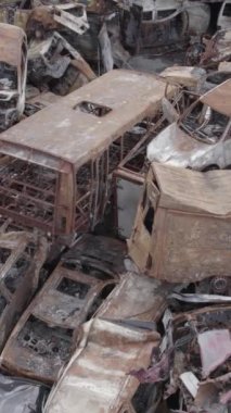 Bu stok dikey video Irpin, Bucha bölgesinde gri, düz, renksiz, yanmış arabaları gösteriyor.