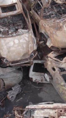 Bu stok dikey video Irpin, Bucha bölgesinde gri, düz, renksiz, yanmış arabaları gösteriyor.