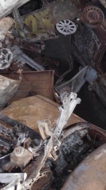 Bu stok dikey video Irpin, Bucha bölgesinde gri, düz, renksiz, yanmış arabaları gösteriyor.