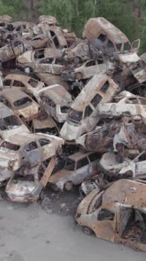 Bu stok dikey video Irpin, Bucha bölgesinde gri, düz, renksiz, yanmış arabaları gösteriyor.