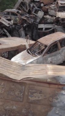 Bu stok dikey video Irpin, Bucha bölgesinde gri, düz, renksiz, yanmış arabaları gösteriyor.