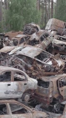 Bu stok dikey video Irpin, Bucha bölgesinde gri, düz, renksiz, yanmış arabaları gösteriyor.