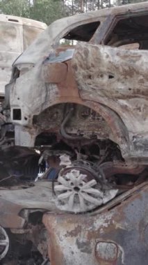 Bu stok dikey video Irpin, Bucha bölgesinde gri, düz, renksiz, yanmış arabaları gösteriyor.