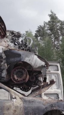 Bu stok dikey video Irpin, Bucha bölgesinde gri, düz, renksiz, yanmış arabaları gösteriyor.
