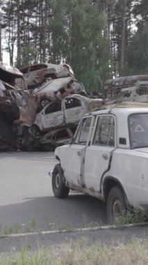 Bu stok dikey video Irpin, Bucha bölgesinde gri, düz, renksiz, yanmış arabaları gösteriyor.