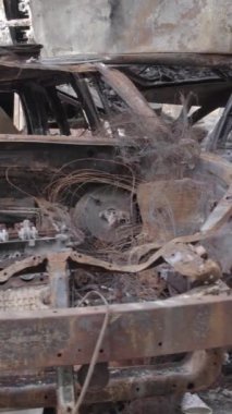 Bu stok dikey video Irpin, Bucha bölgesinde gri, düz, renksiz, yanmış arabaları gösteriyor.