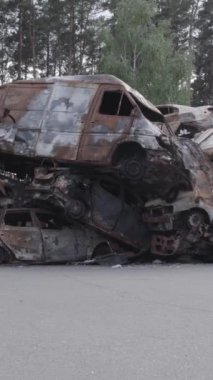 Bu stok dikey video Irpin, Bucha bölgesinde gri, düz, renksiz, yanmış arabaları gösteriyor.