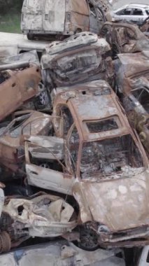 Bu stok dikey video Irpin, Bucha bölgesinde gri, düz, renksiz, yanmış arabaları gösteriyor.