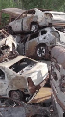 Bu stok dikey video Irpin, Bucha bölgesinde gri, düz, renksiz, yanmış arabaları gösteriyor.