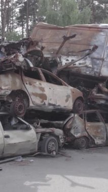 Bu stok dikey video Irpin, Bucha bölgesinde gri, düz, renksiz, yanmış arabaları gösteriyor.