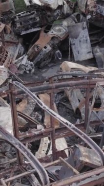 Bu stok dikey video Irpin, Bucha bölgesinde gri, düz, renksiz, yanmış arabaları gösteriyor.