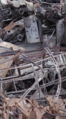 Bu stok dikey video Irpin, Bucha bölgesinde gri, düz, renksiz, yanmış arabaları gösteriyor.