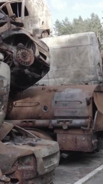 Bu stok dikey video Irpin, Bucha bölgesinde gri, düz, renksiz, yanmış arabaları gösteriyor.