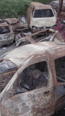 Bu stok dikey video Irpin, Bucha bölgesinde gri, düz, renksiz, yanmış arabaları gösteriyor.