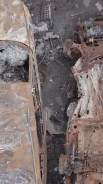 Bu stok dikey video Irpin, Bucha bölgesinde gri, düz, renksiz, yanmış arabaları gösteriyor.