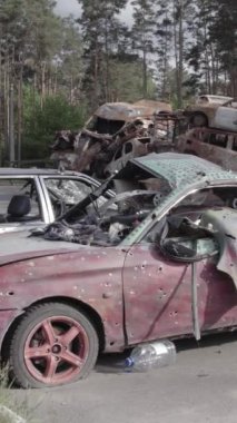 Bu stok dikey video Irpin, Bucha bölgesinde gri, düz, renksiz, yanmış arabaları gösteriyor.