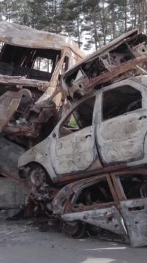 Bu stok dikey video Irpin, Bucha bölgesinde gri, düz, renksiz, yanmış arabaları gösteriyor.